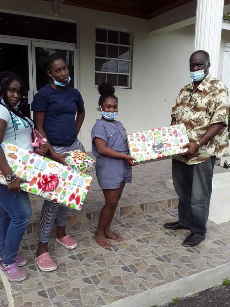 Children and an adult with wrapped gifts outside the building