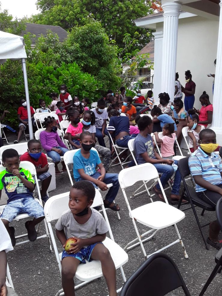 Children seated together outside the community building